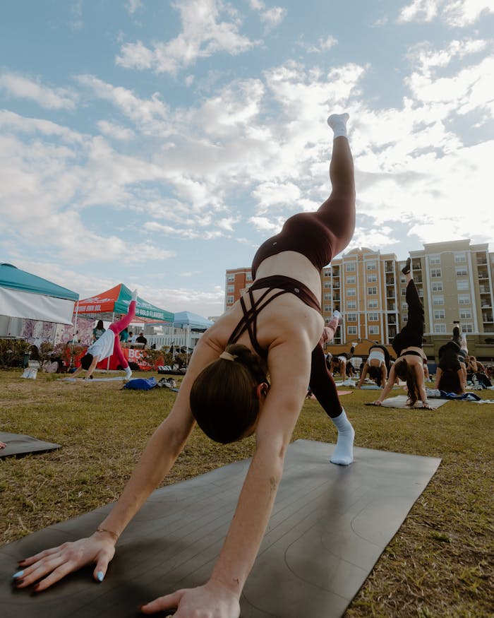 Group of women practicing yoga outdoors in a city park. Fitness and wellness in urban lifestyles.