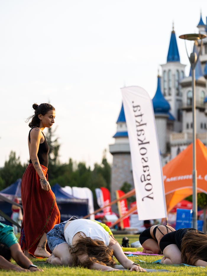Women participating in a yoga class at a park in Eskişehir, Türkiye, with a fairytale castle in the background.